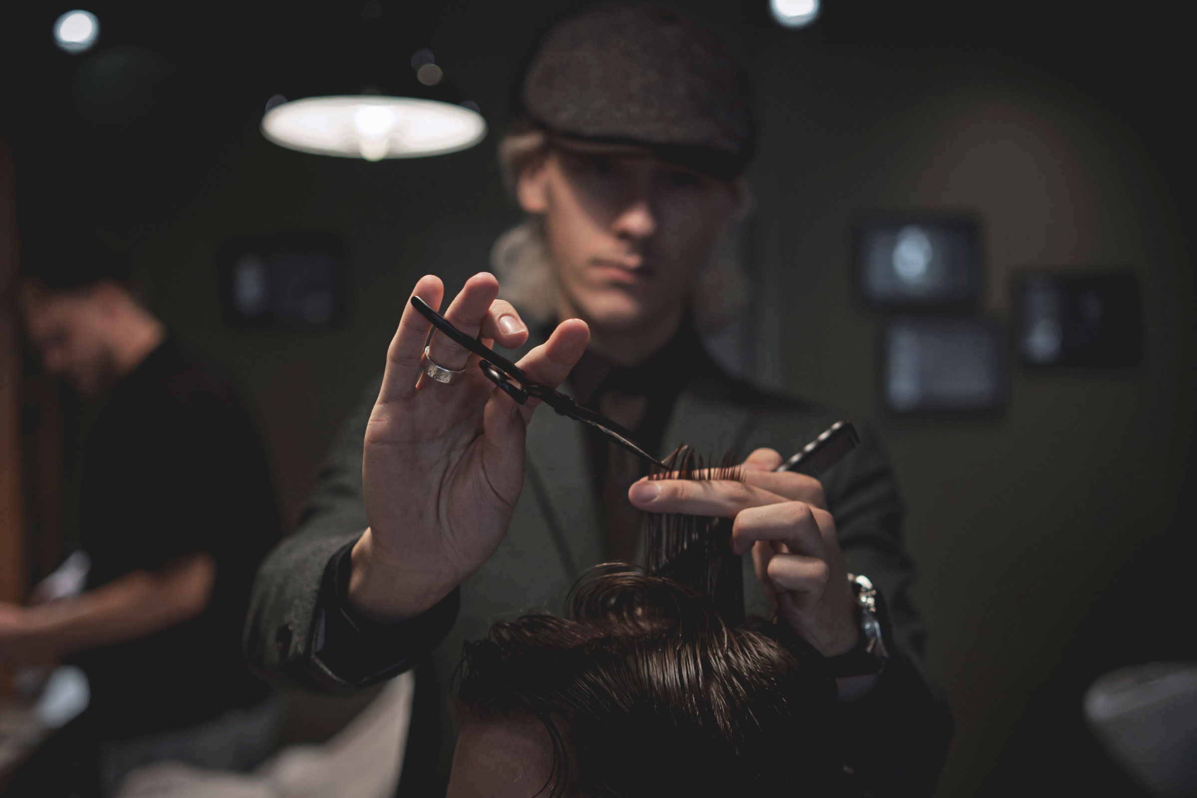 Een professionele barber knipt zorgvuldig het haar van een klant in een stijlvolle kapsalon. De afbeelding benadrukt vakmanschap, precisie en een ontspannen sfeer.