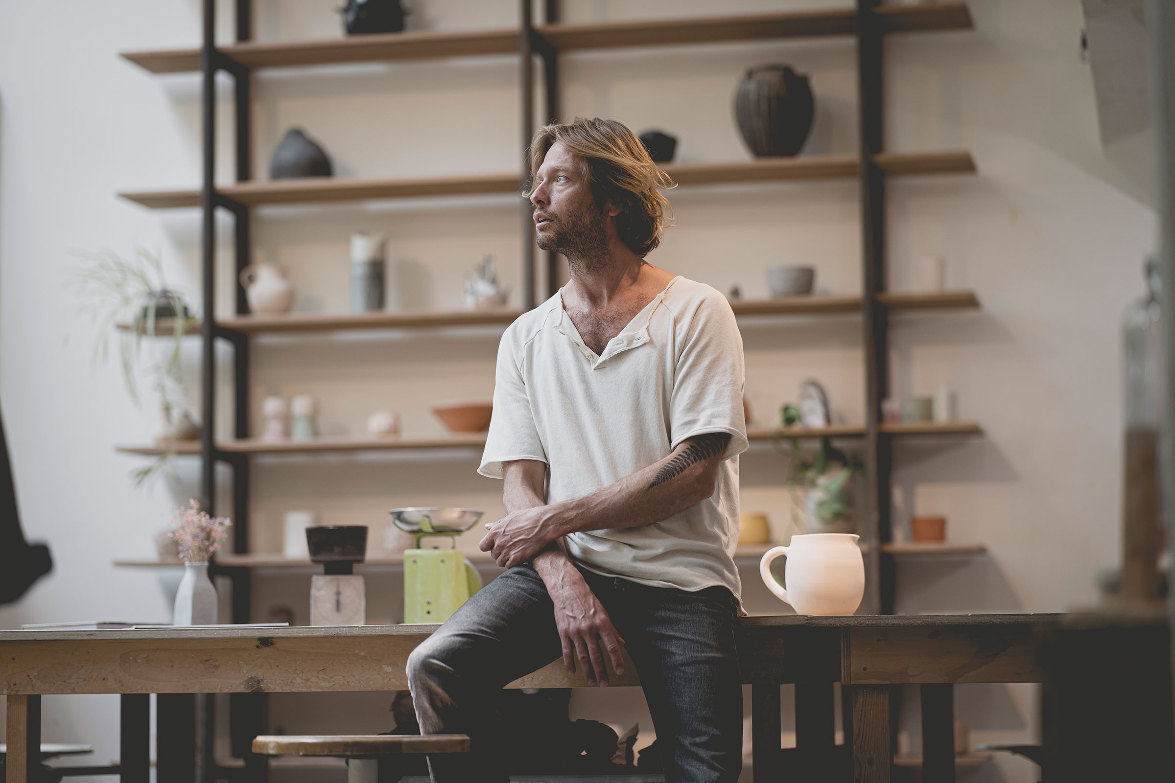 Professioneel zakelijk portret van een man in een creatieve studio met keramiek en designobjecten, gefotografeerd in Amsterdam. Authentieke lifestyle fotografie met oog voor detail en sfeer.